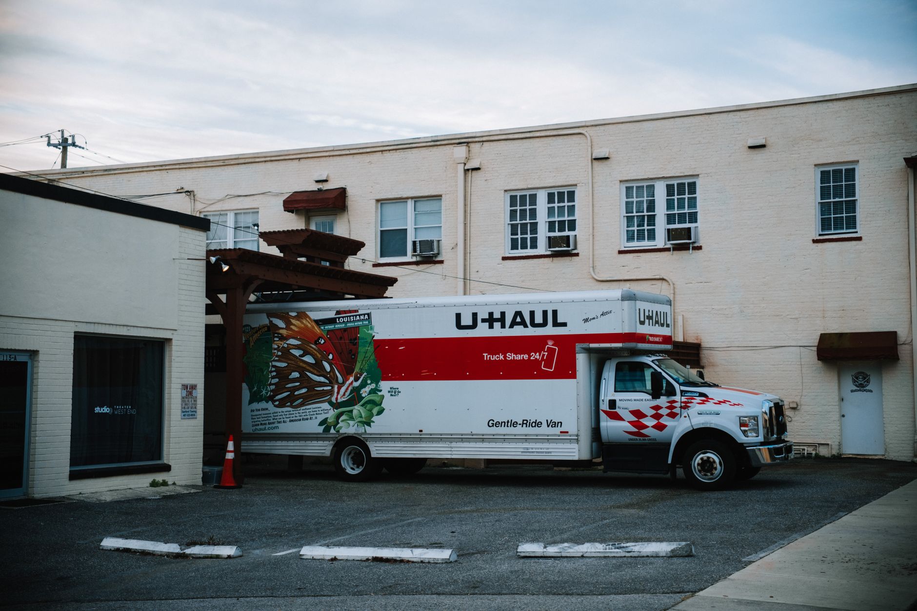 A large box truck parked beside a pale brick building