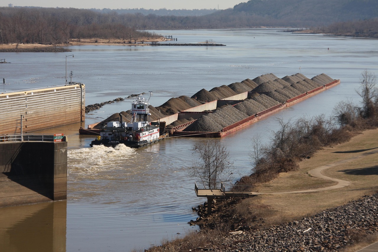 A towboat pushing gravel barges out of a river lock